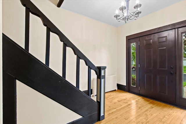 330 1st St, Port Edwards, WI 54469 - entrance foyer with radiator heating unit, stairs, a chandelier, and light wood-style flooring