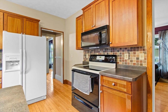 330 1st St, Port Edwards, WI 54469 - kitchen with white refrigerator with ice dispenser, black microwave, range with electric cooktop, tasteful backsplash, and light wood-style flooring