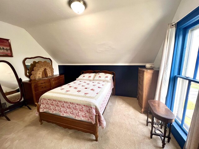 bedroom with vaulted ceiling and light carpet