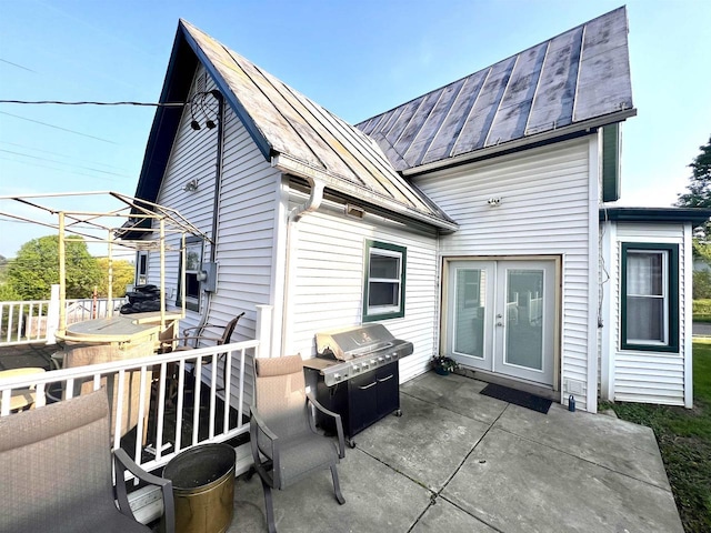 rear view of property featuring a standing seam roof, french doors, a patio, and metal roof