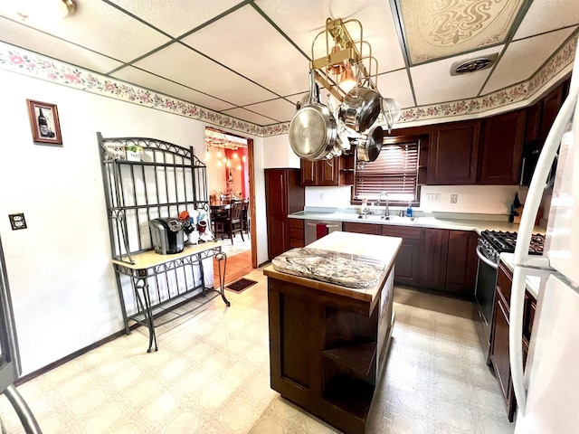 kitchen featuring open shelves, light countertops, stainless steel dishwasher, a sink, and light floors