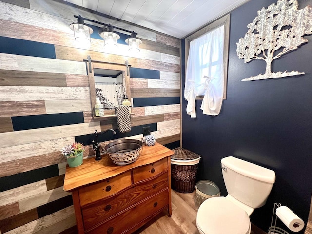 full bathroom with wood walls, toilet, wood finished floors, vanity, and a shower with curtain