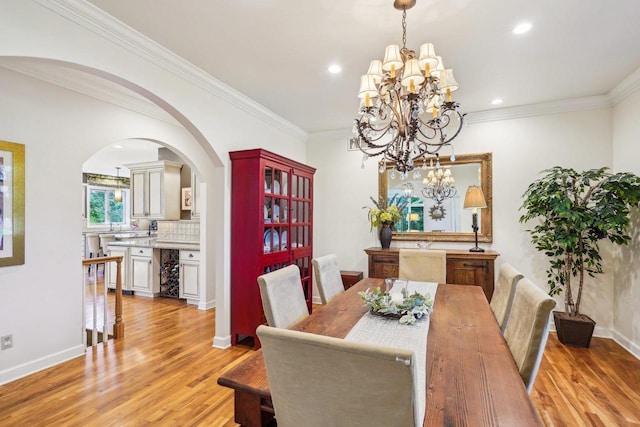 W8849 Deer Run Trl, Cambridge, WI 53523 - dining area featuring light wood-type flooring, a chandelier, crown molding, arched walkways, and baseboards
