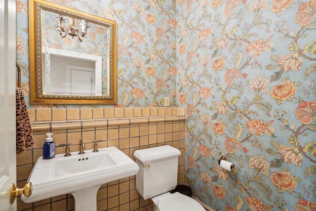 W8849 Deer Run Trl, Cambridge, WI 53523 - bathroom with wallpapered walls, toilet, tile walls, a wainscoted wall, and a sink
