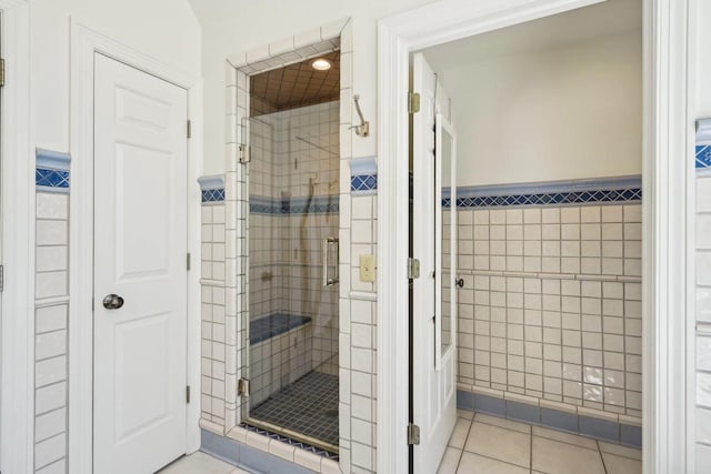 W8849 Deer Run Trl, Cambridge, WI 53523 - bathroom featuring tile walls, a stall shower, tile patterned flooring, a wainscoted wall, and a closet