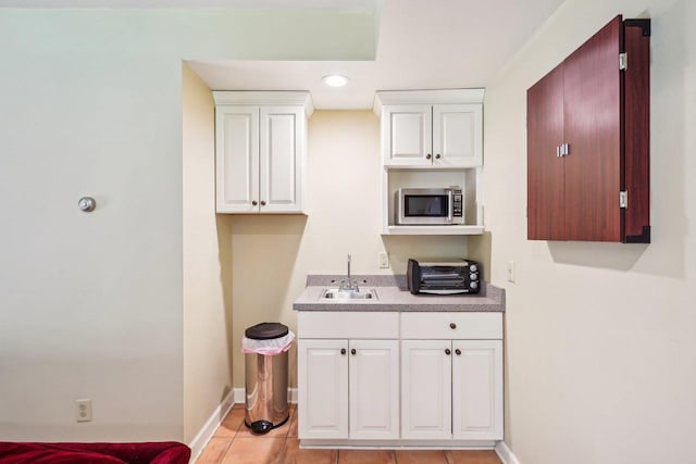 W8849 Deer Run Trl, Cambridge, WI 53523 - kitchen featuring a sink, stainless steel microwave, baseboards, light tile patterned flooring, and white cabinetry