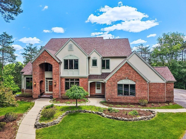W8849 Deer Run Trl, Cambridge, WI 53523 - tudor-style house featuring stucco siding, a front lawn, brick siding, and roof with shingles