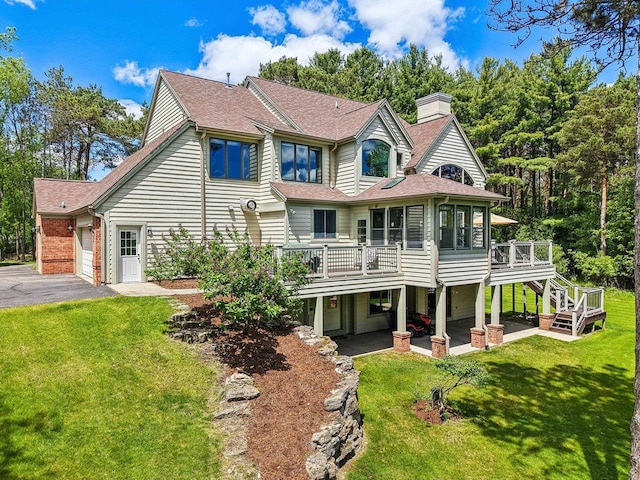 W8849 Deer Run Trl, Cambridge, WI 53523 - back of property featuring a deck, a shingled roof, a garage, asphalt driveway, and a sunroom