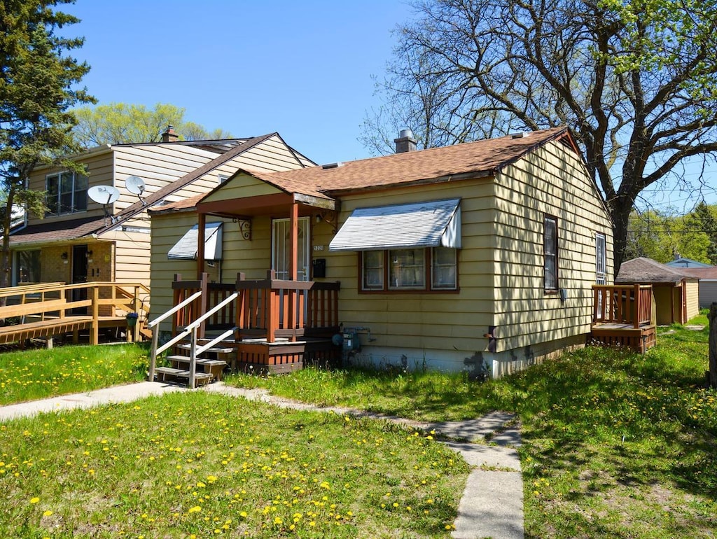 bungalow-style home featuring a front yard, a wooden deck, and a chimney