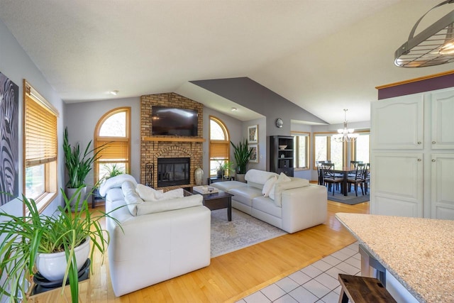 1502 Marquardt Rd, Wausau, WI 54403 - living area with a chandelier, lofted ceiling, a brick fireplace, and light wood-style flooring