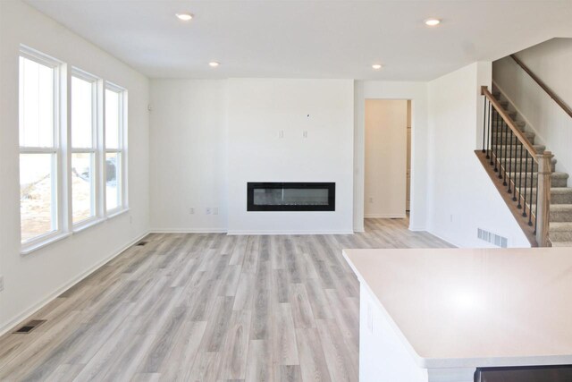 4004 Banbury St, Windsor, WI 53598 - unfurnished living room with plenty of natural light, stairs, light wood-type flooring, a glass covered fireplace, and recessed lighting