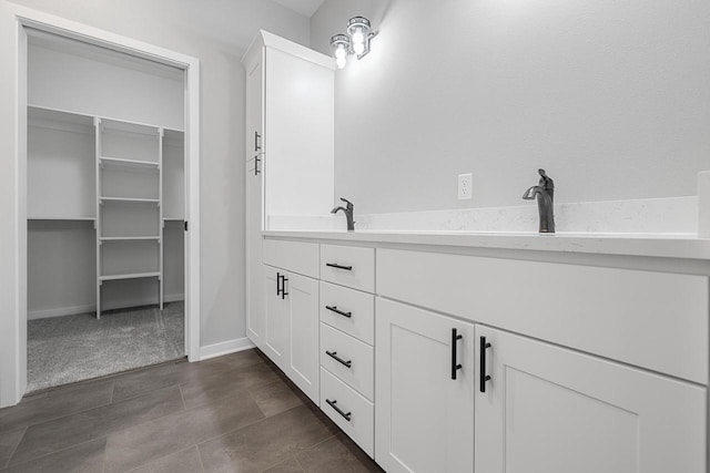 653 Lambert Ct Unit 2-2, Slinger, WI 53086 - full bath featuring a walk in closet, double vanity, baseboards, and tile patterned flooring