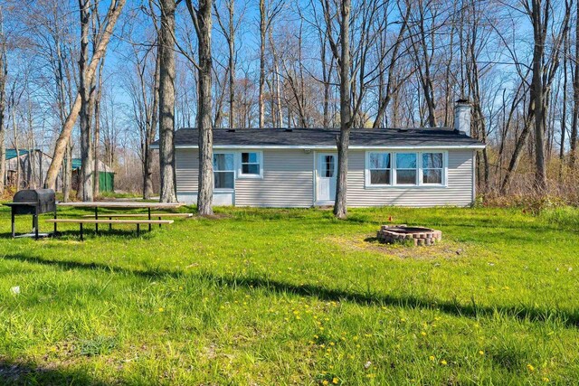 229 Bay Rd, Peshtigo, WI 54147 - back of property with an outdoor fire pit, a chimney, and a yard
