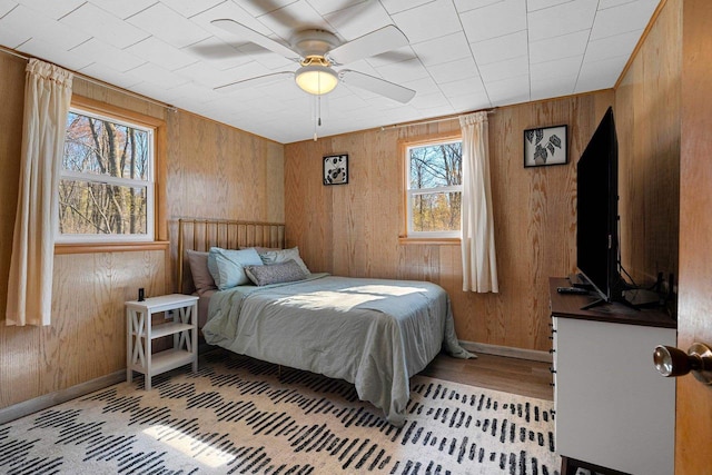 229 Bay Rd, Peshtigo, WI 54147 - bedroom featuring wood walls, baseboards, light wood-style flooring, and a ceiling fan