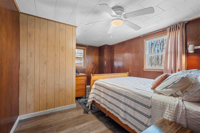 229 Bay Rd, Peshtigo, WI 54147 - bedroom featuring wooden walls, wood finished floors, baseboards, and ceiling fan