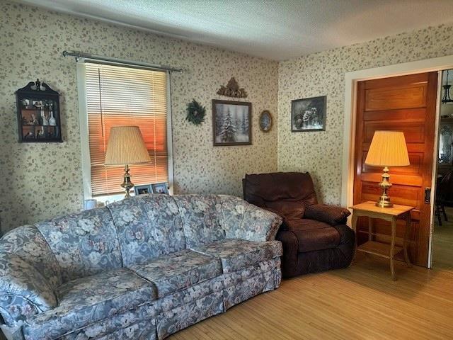 110 Hewett St, Neillsville, WI 54456 - living room featuring wood finished floors, wallpapered walls, and a textured ceiling