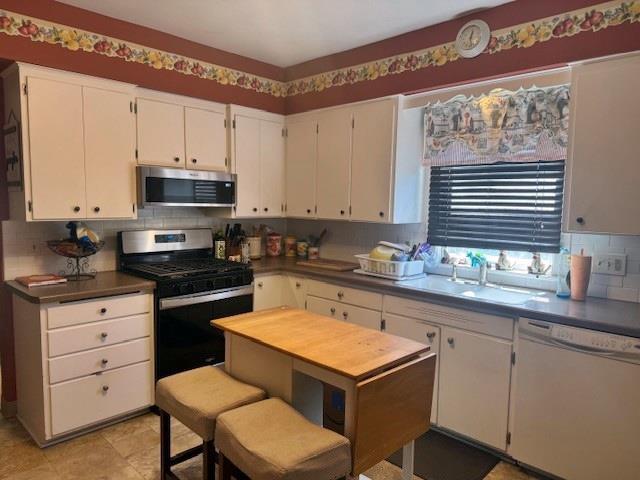 110 Hewett St, Neillsville, WI 54456 - kitchen featuring stainless steel appliances, backsplash, white cabinets, and a sink
