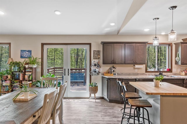 kitchen featuring a sink, dark brown cabinetry, a kitchen breakfast bar, butcher block countertops, and recessed lighting