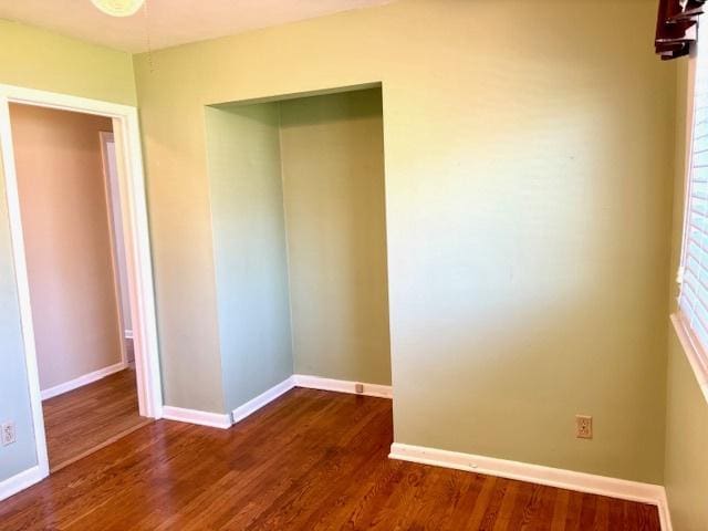 unfurnished bedroom featuring dark wood-type flooring, baseboards, and a closet