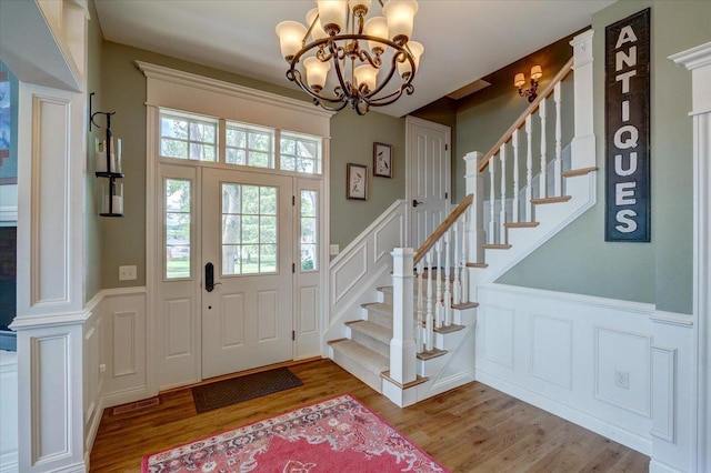 W11601 Demynck Rd, Lodi, WI 53555 - foyer entrance featuring a decorative wall, wood finished floors, a chandelier, stairs, and a wainscoted wall