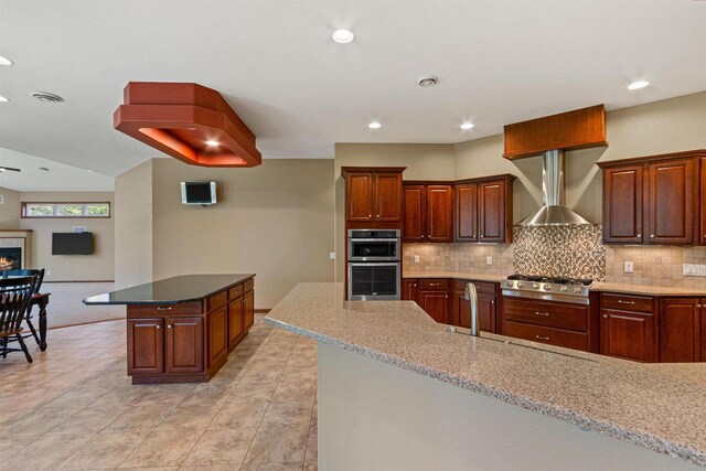 6056 Sharonwood Ln, Stevens Point, WI 54482 - kitchen featuring appliances with stainless steel finishes, wall chimney range hood, tasteful backsplash, light stone counters, and recessed lighting