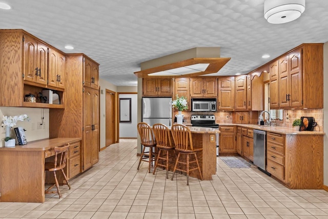kitchen featuring stainless steel appliances, a breakfast bar, light countertops, brown cabinets, and tasteful backsplash