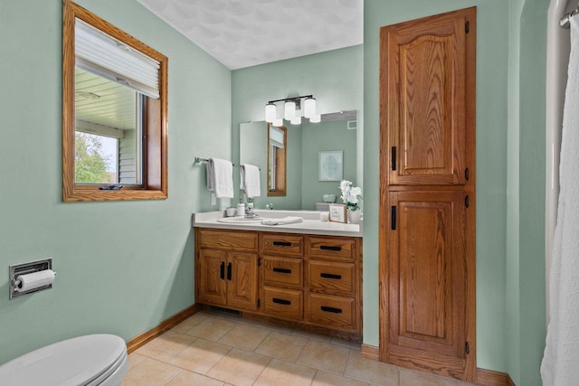 bathroom with tile patterned flooring, baseboards, toilet, and vanity