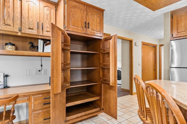 kitchen with freestanding refrigerator, open shelves, light tile patterned flooring, light countertops, and washer / clothes dryer