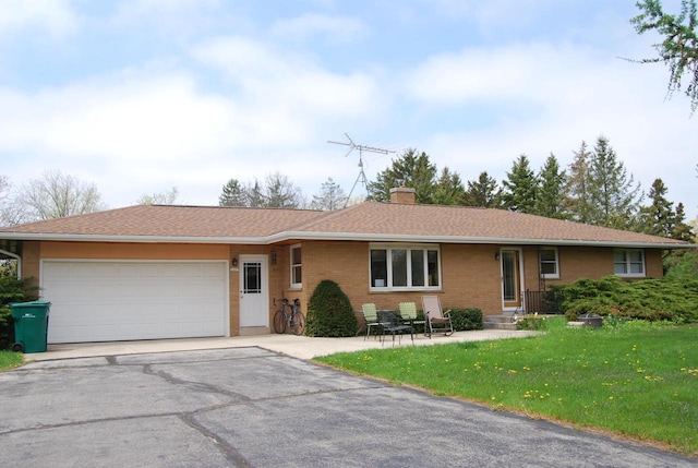 3207 County Rd W, Port Washington, WI 53074 - single story home with asphalt driveway, a garage, brick siding, a front lawn, and a chimney