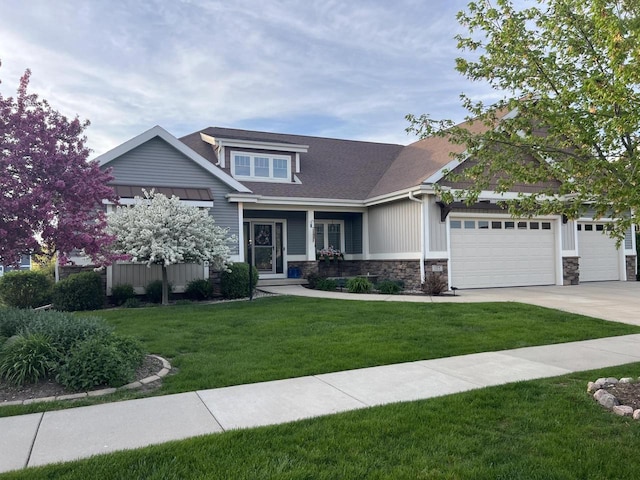 1115 Ireland Dr, Waunakee, WI 53597 - craftsman-style home with stone siding, a front lawn, an attached garage, driveway, and a shingled roof