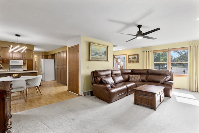2425 Sandstone Ct, Oshkosh, WI 54904 - living room with light carpet, a ceiling fan, and a chandelier