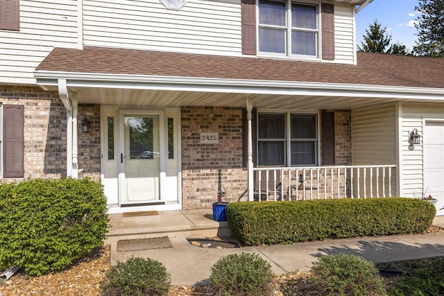 2425 Sandstone Ct, Oshkosh, WI 54904 - doorway to property with covered porch, brick siding, roof with shingles, and a garage