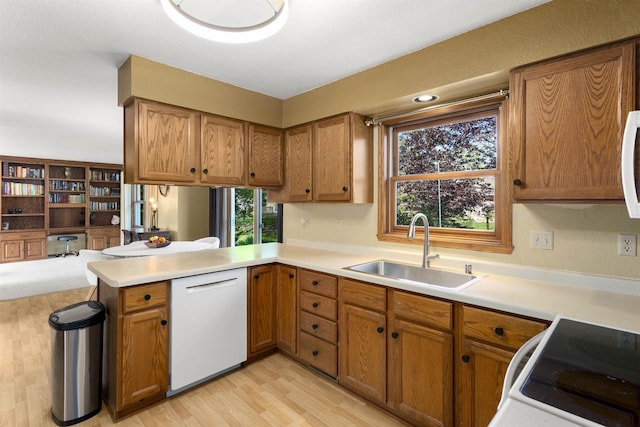 2425 Sandstone Ct, Oshkosh, WI 54904 - kitchen featuring white appliances, a sink, brown cabinets, and a peninsula