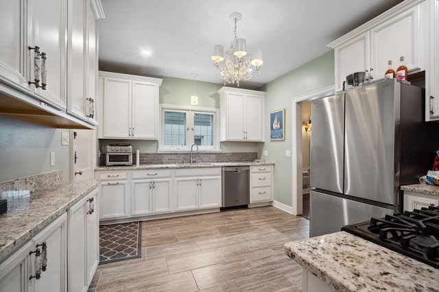 2017 N Terrace Ave, Milwaukee, WI 53202 - kitchen featuring stainless steel appliances, a sink, white cabinets, pendant lighting, and a chandelier