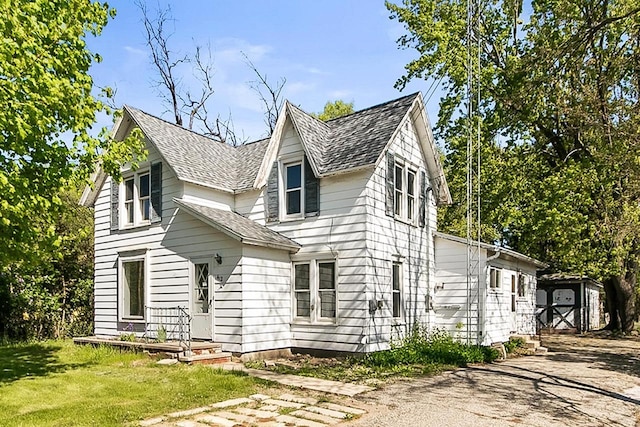 412 W Chestnut St, Pardeeville, WI 53954 - view of front facade with roof with shingles, asphalt driveway, a front yard, and an outbuilding