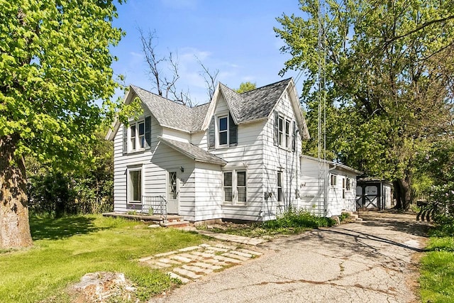 412 W Chestnut St, Pardeeville, WI 53954 - view of property exterior featuring asphalt driveway, a yard, a shingled roof, and an outbuilding