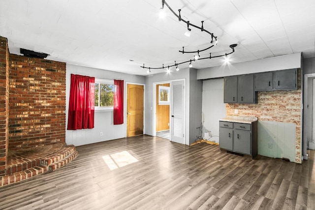 412 W Chestnut St, Pardeeville, WI 53954 - unfurnished living room with dark wood-style floors, rail lighting, and brick wall
