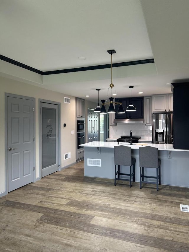 1341 S Wilson Ave Unit 10-4, Hartford, WI 53027 - kitchen with stainless steel fridge, light countertops, a kitchen bar, wood finished floors, and decorative light fixtures