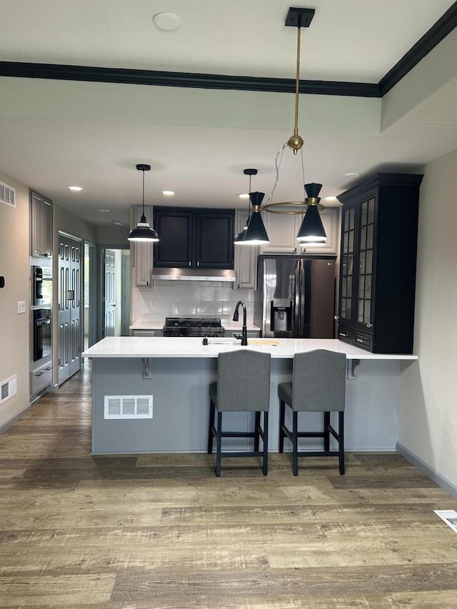 1341 S Wilson Ave Unit 10-4, Hartford, WI 53027 - kitchen with black fridge with ice dispenser, stainless steel double oven, ornamental molding, light countertops, and backsplash