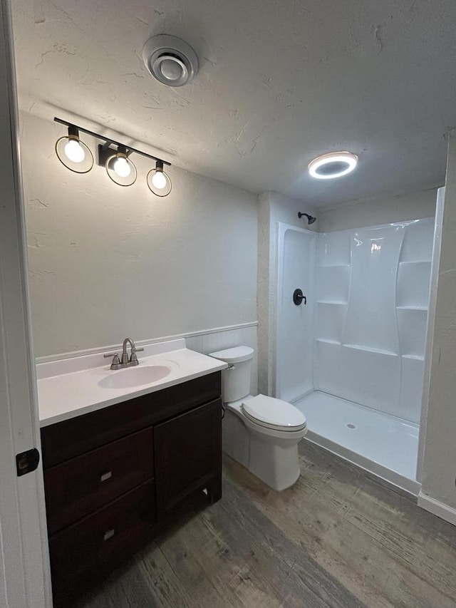 1341 S Wilson Ave Unit 10-4, Hartford, WI 53027 - bathroom with wood finished floors, a stall shower, vanity, toilet, and wainscoting