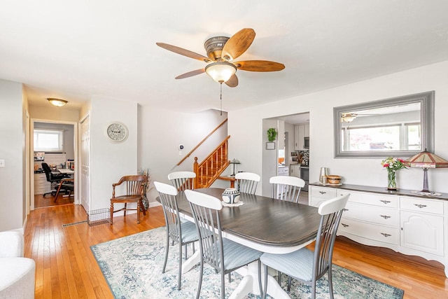 dining area featuring stairway, light wood-style floors, a desk, and ceiling fan