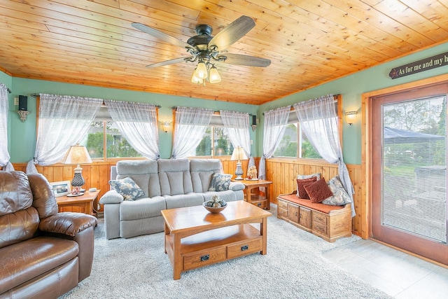 living area with a wainscoted wall, wood ceiling, a ceiling fan, carpet flooring, and wood walls