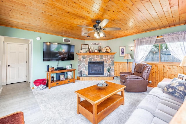 living room with wood ceiling, a ceiling fan, wood walls, a wainscoted wall, and a fireplace