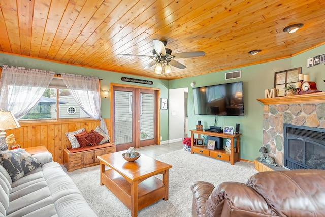 carpeted living room with wooden ceiling, a fireplace, a ceiling fan, and wooden walls