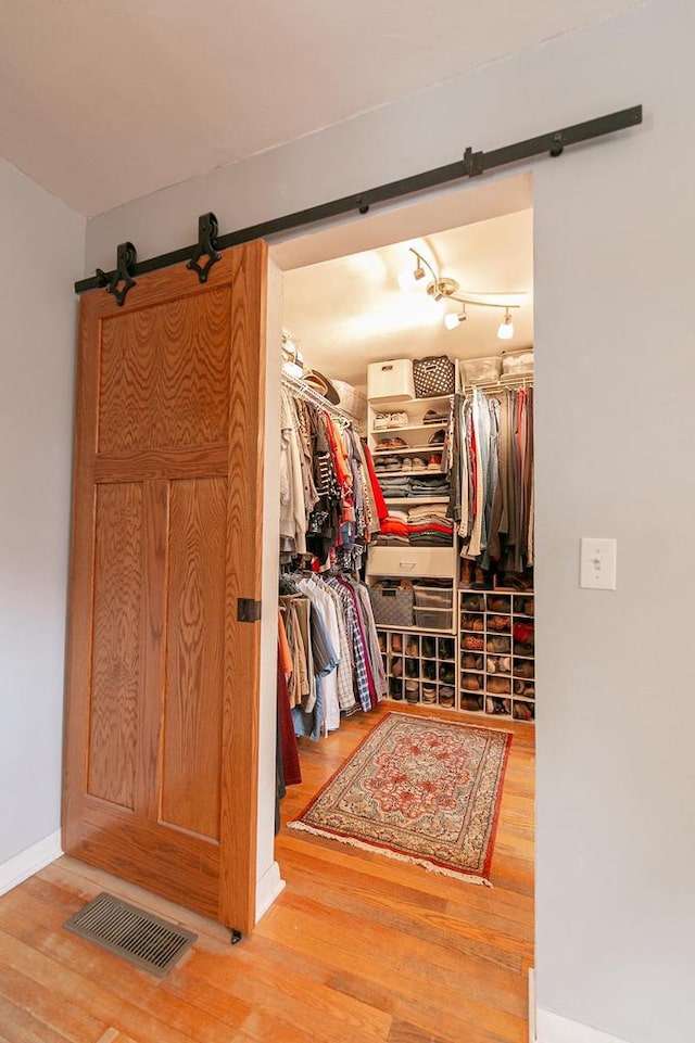 walk in closet with a barn door and wood finished floors