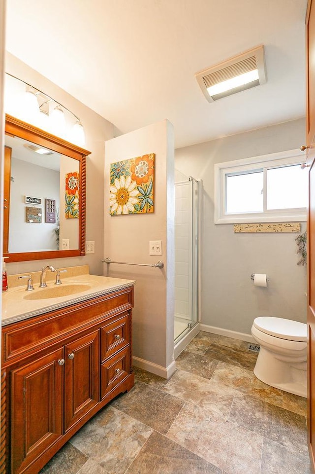 full bathroom with stone finish floors, a stall shower, toilet, vanity, and baseboards