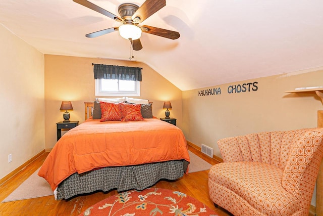 bedroom with wood finished floors, vaulted ceiling, baseboards, and a ceiling fan