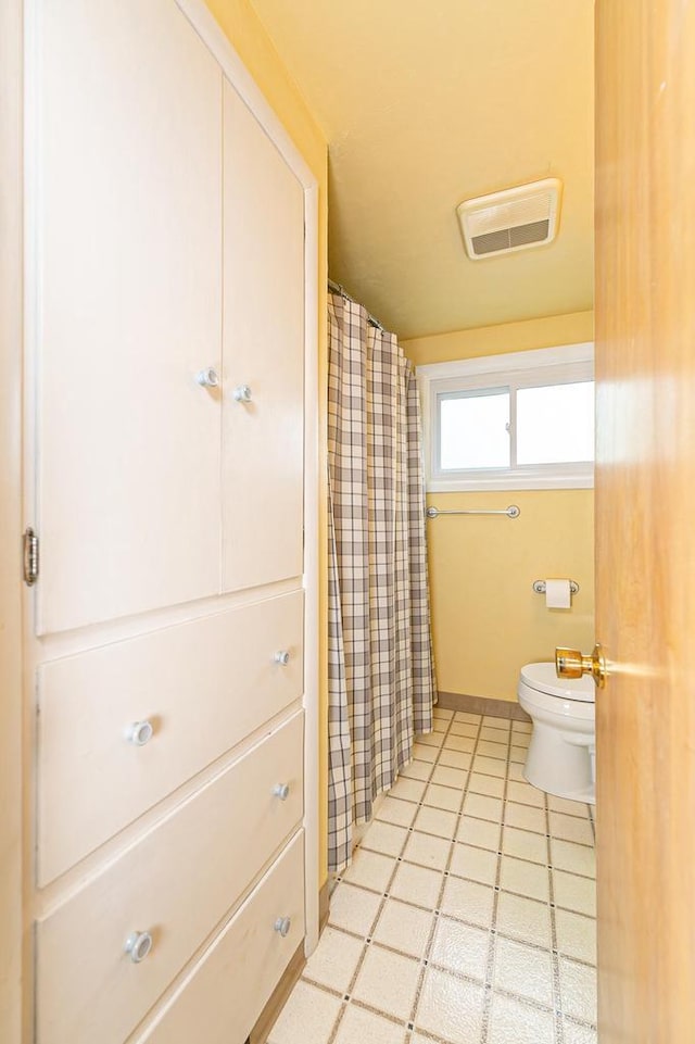 bathroom with toilet, tile patterned floors, baseboards, and a shower with curtain