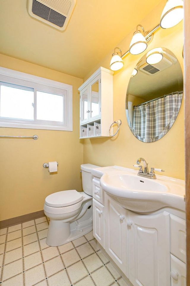 bathroom with toilet, vanity, and tile patterned floors