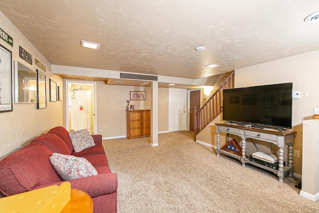 carpeted living area with baseboards, stairs, and a textured ceiling